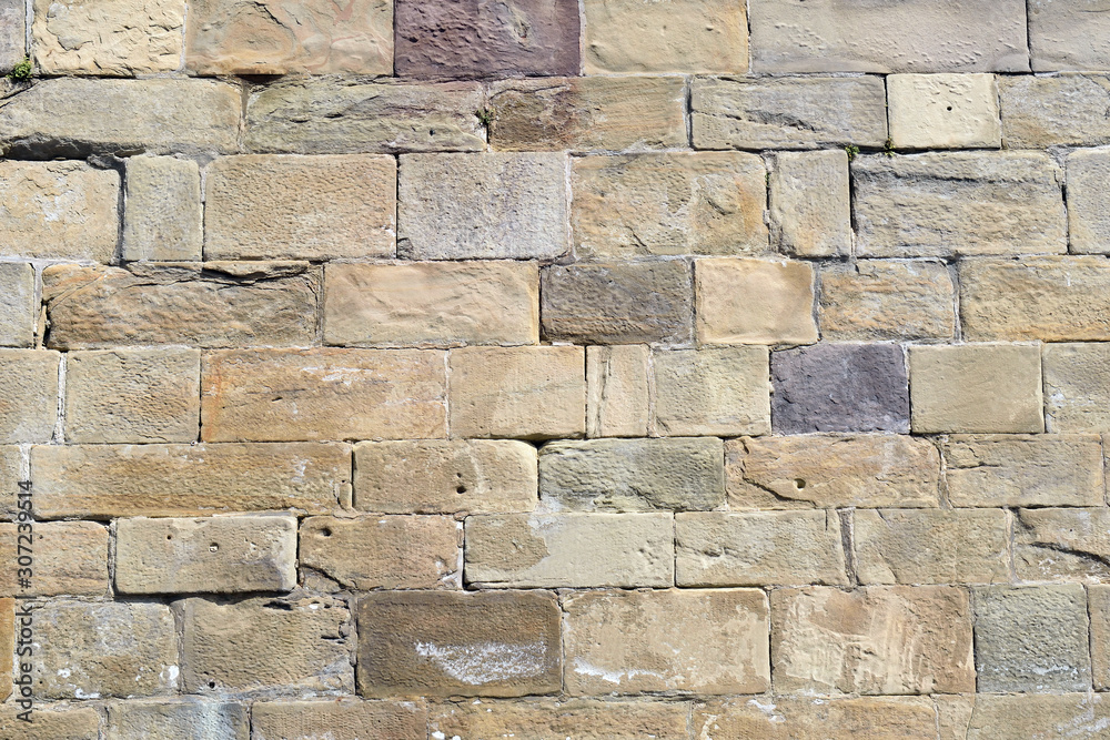 Obraz premium Old Multi-coloured Stone Wall in Bright Sun 