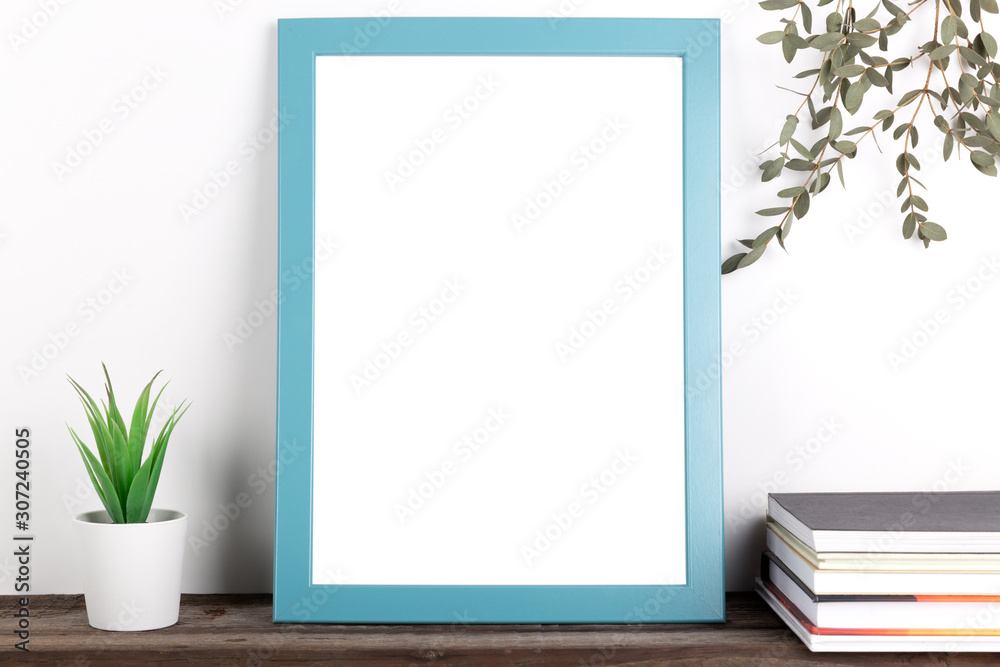 Interior poster mock up with vertical wooden frame, books and house plants on white wall background Interior poster mock up with vertical wooden frame, books and house plants on white wall background