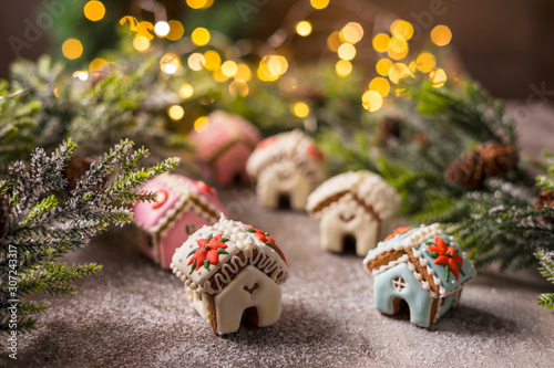 Gingerbread house on the background of a Christmas tree and a lie garland. Handling the effect of snowfall.