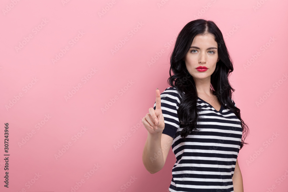 Young woman pointing at something on a pink background