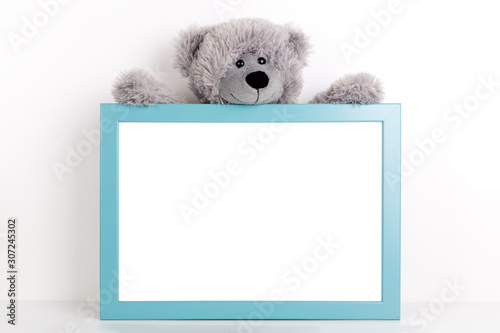 Interior poster mock up for nurcery, children's room with vertical wooden frame and teddy bear on white wall background photo