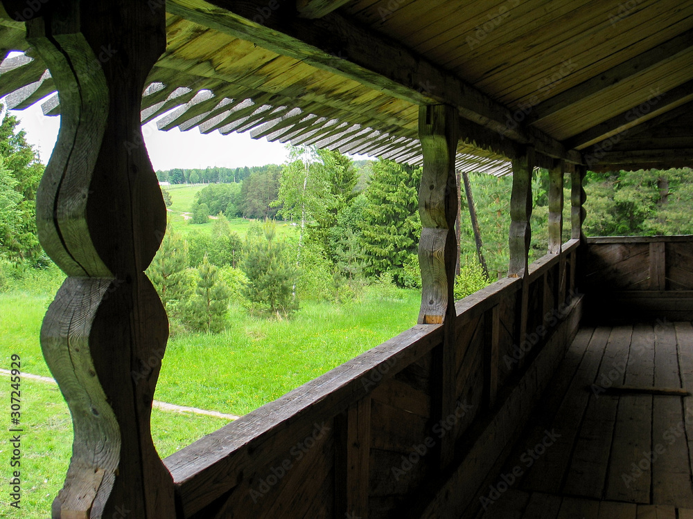 View of the green forest from the wooden carved balcony of an old building