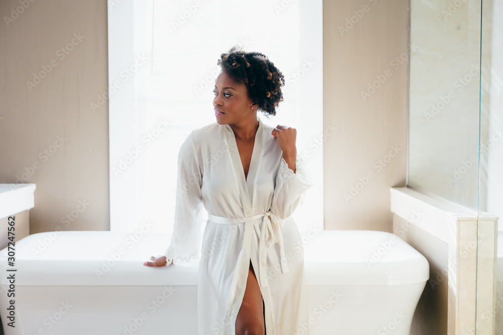 Woman with natural hair wearing robe and resting against bathtub Woman with natural hair wearing robe and resting against bathtub