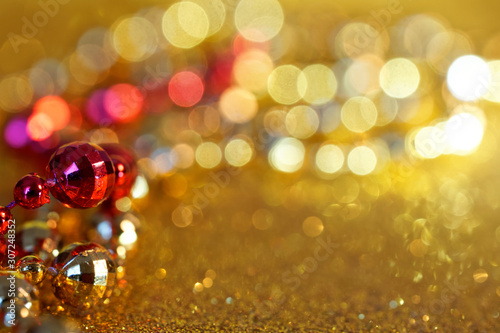 Festive abstract background of golden and red Christmas tinsel and many yellow lights. Defocus show. Blank for greeting card. Free space for an inscription