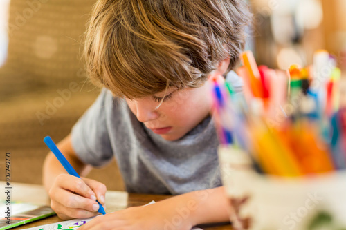 6 year old boy drawing amoung colorful pens photo