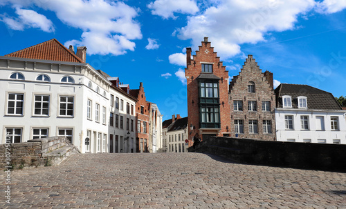 Scenic city view of Bruges canal with beautiful medieval colored houses .