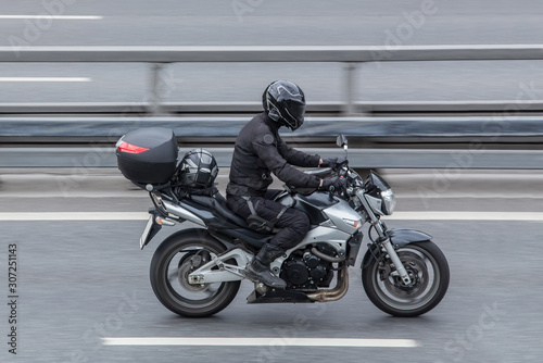 Motorcyclist in a helmet rides a motorcycle on the road. photo