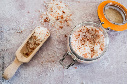 High angle close up of wooden spoon and glass jar with coarse salt.