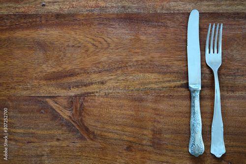Background of a dark wooden table top, with an old fork and an old knife and plenty of space for text