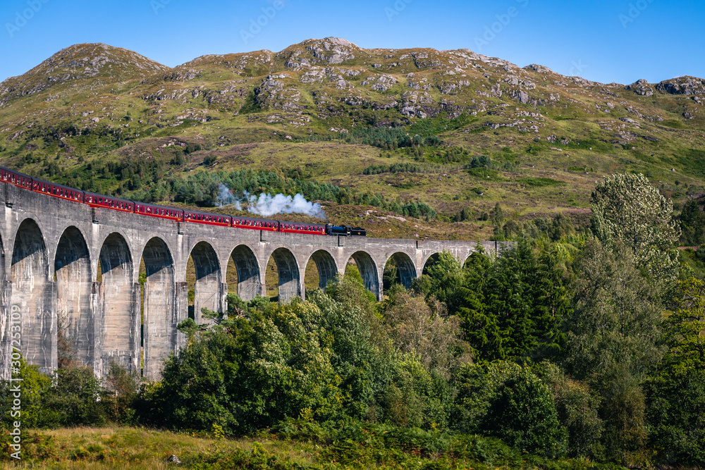 View on famous Glenfinnan viaduct from Harry Potter movies with red Jacobi train, Scotland