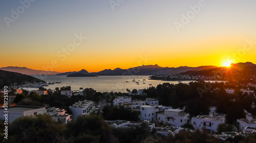 Bright colorful sunset in the beautiful bay of the Aegean sea with islands, mountains and boats. Summer holiday concept and travel background © OLAYOLA