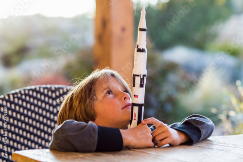 A boy playing with a toy Nasa Saturn 5 rocket, day dreaming about space flight. photo