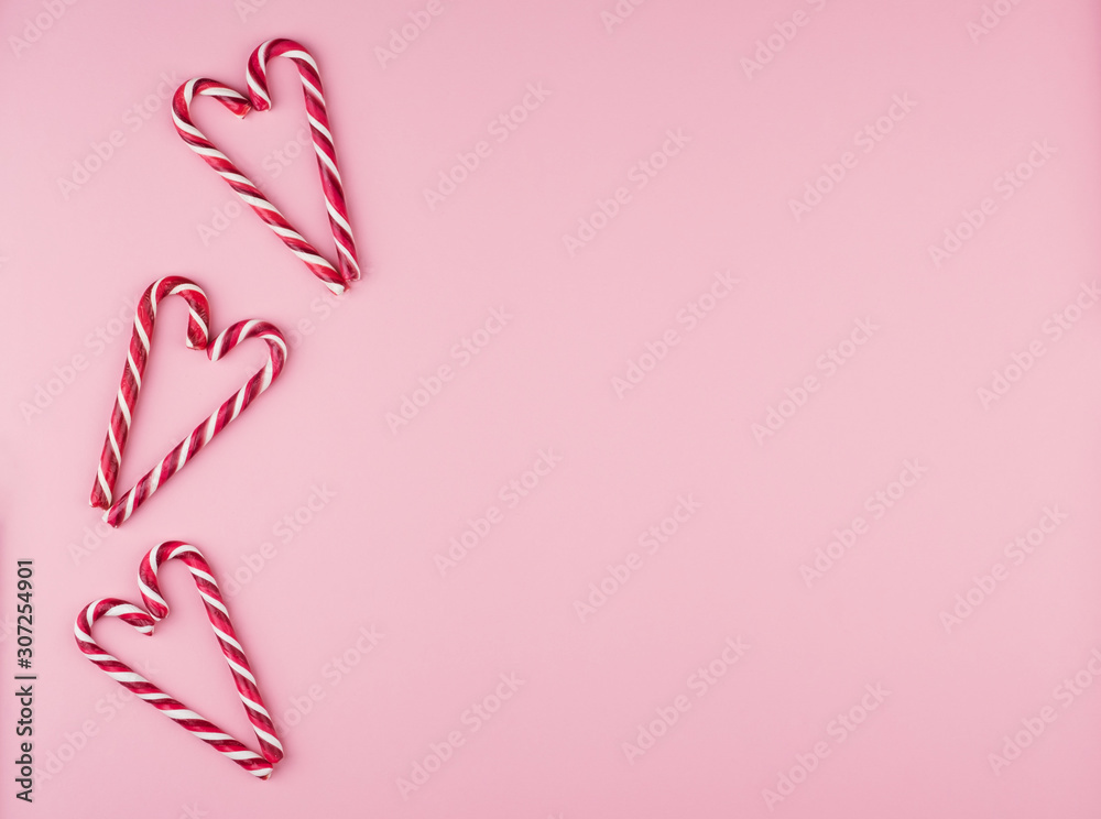 Candy cane laid out in the form of a heart on a pink background. Candy cane laid out in the form of a heart on a pink background.