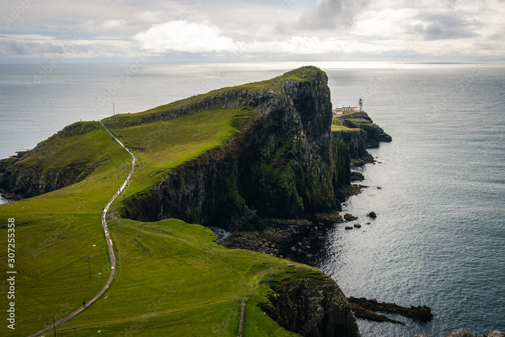 Famous lighthouse on isle of Skye in Scotland, Point nest, view over the approaching path, over the green meadow Famous lighthouse on isle of Skye in Scotland, Point nest, view over the approaching path, over the green meadow