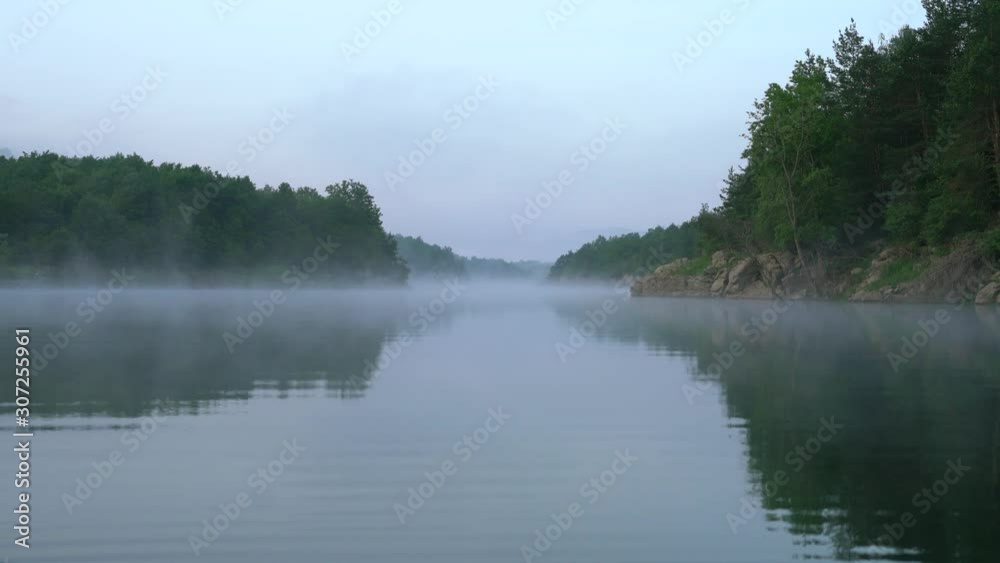 Misty morning with fog over calm river surface