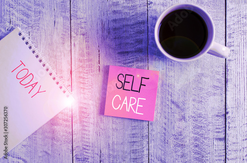 Conceptual hand writing showing Self Care. Concept meaning Give comfort to your own body without professional consultant Stationary placed next to a coffee cup above wooden table photo