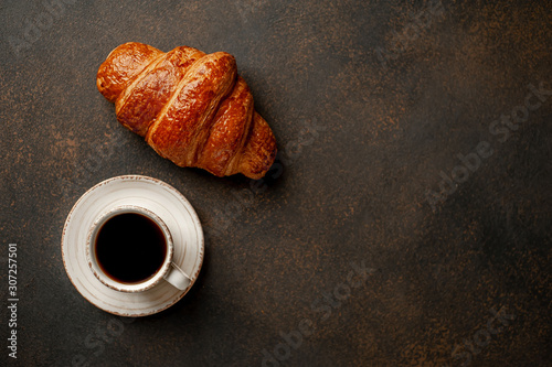 coffee and croissant on a stone table with copy space for your text, early breakfast concept