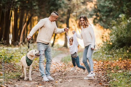 Happy beautiful family with dog labrador is having fun together walking the in park. © zadorozhna