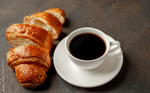 coffee and a large sliced       croissant on a stone table  close-up  early breakfast concept