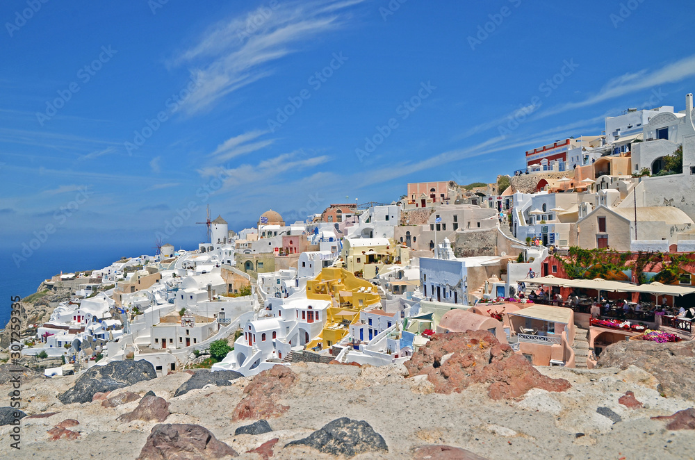Oia town on Santorini island, Greece. Traditional and famous white houses and churches with blue domes over the Caldera, Aegean sea.