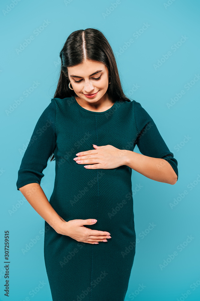 smiling pregnant girl touching belly isolated on blue smiling pregnant girl touching belly isolated on blue