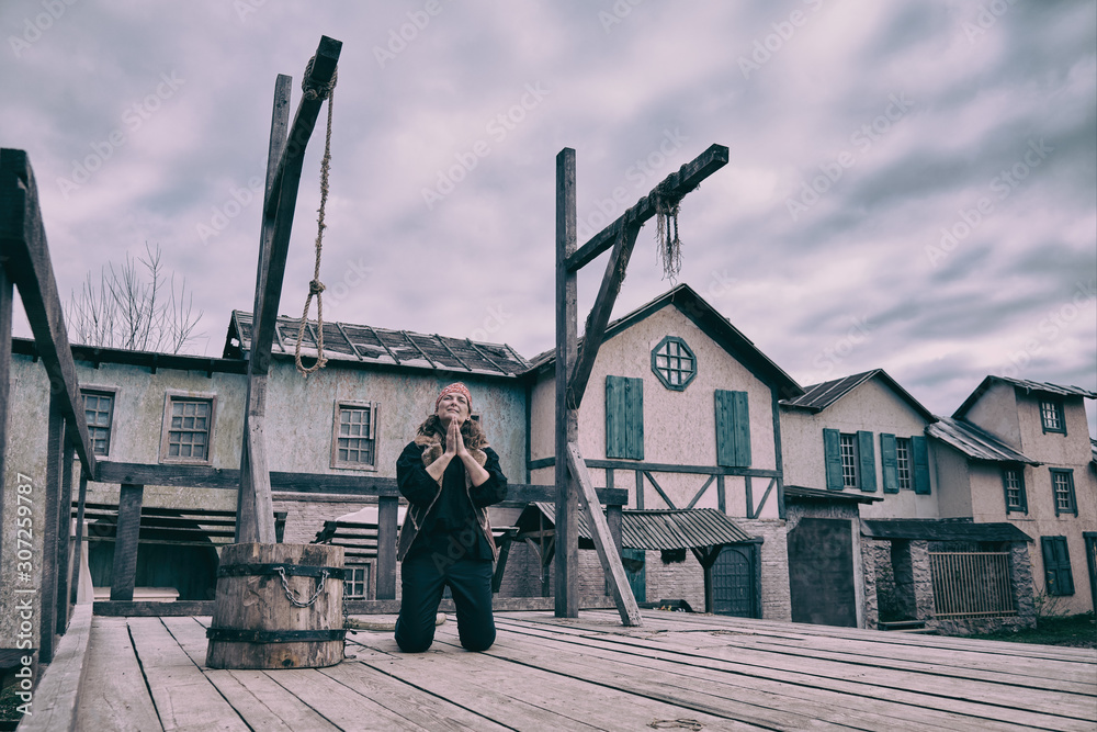 Φωτογραφία A female robber in vintage clothing kneels and prays at the execution site of cr
