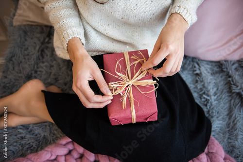 Girl decorates Christmas gift box with beautiful ribbon