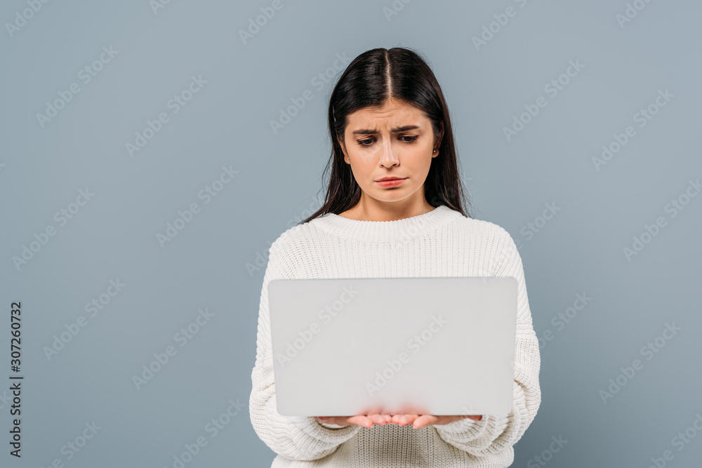 sad pretty brunette girl in white sweater holding laptop isolated on grey sad pretty brunette girl in white sweater holding laptop isolated on grey
