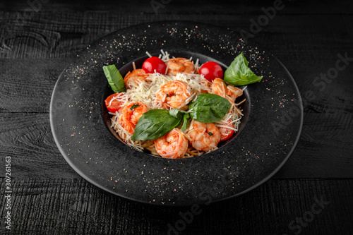Spaghetti salad or pasta with shrimp, cherry tomatoes, cheddar cheese, parmesan, basil and sauce. Nutritious, dietary, fitness food. Black boards background