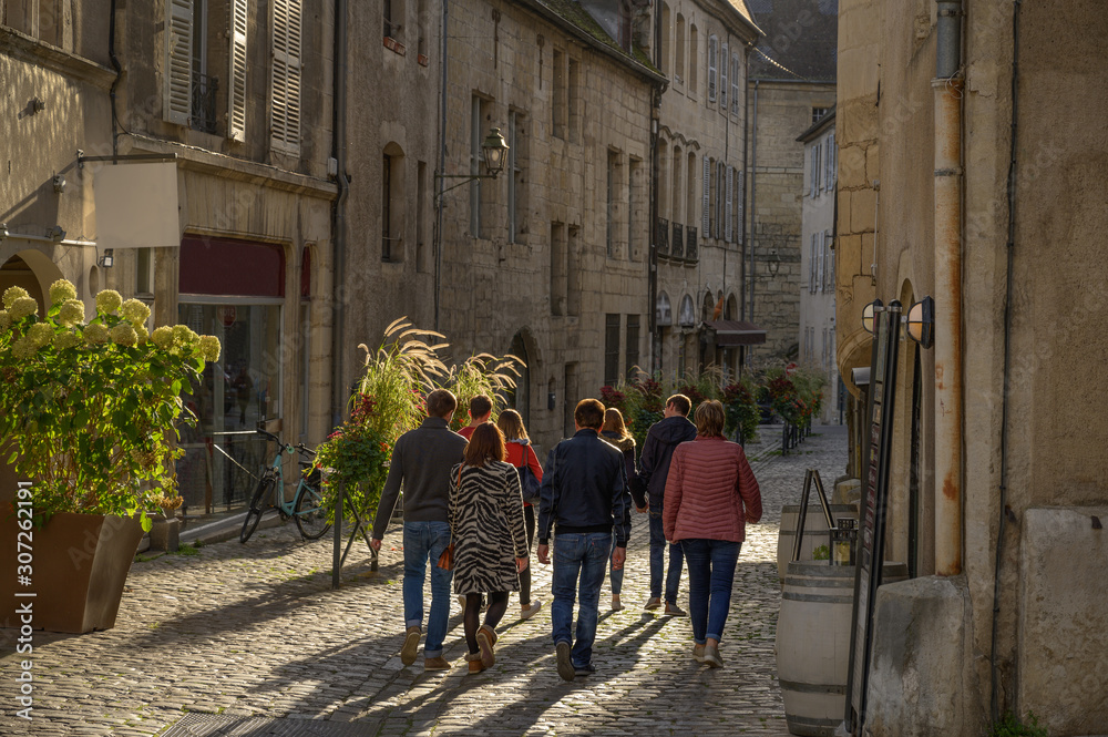 A group of unidentfied people walkin in an old street in the city of Dole in France.