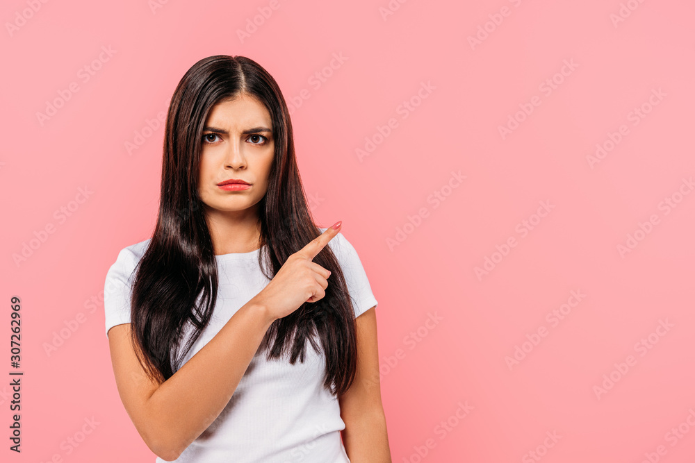 sad pretty brunette girl pointing with finger at copy space isolated on pink sad pretty brunette girl pointing with finger at copy space isolated on pink