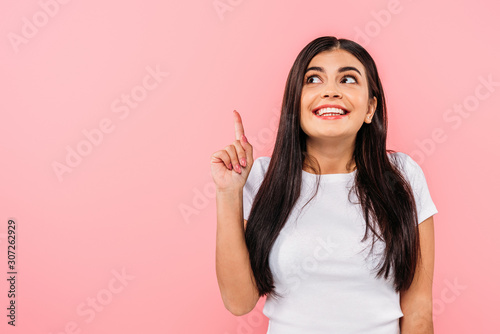 excited pretty brunette girl pointing with finger at copy space isolated on pink © LIGHTFIELD STUDIOS