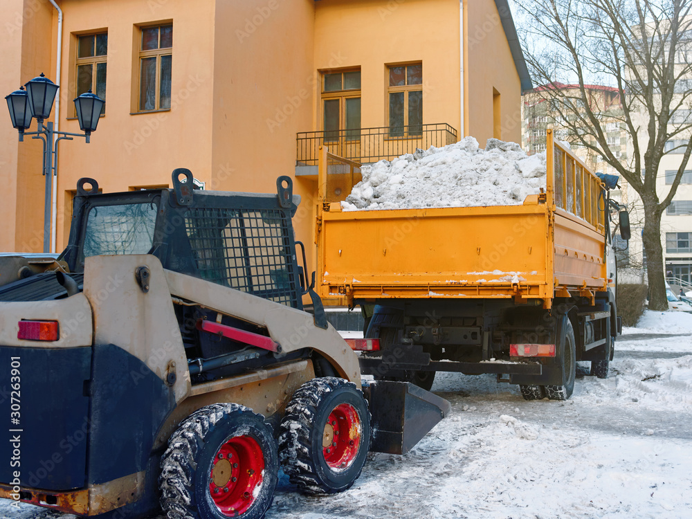 Small loader removing and loading snow into a truck. Skid steer loading ...