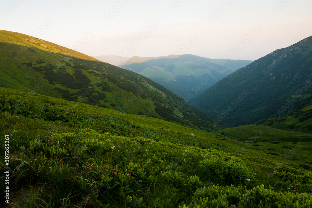 Setting sun shines against hills, beautiful green mountains
