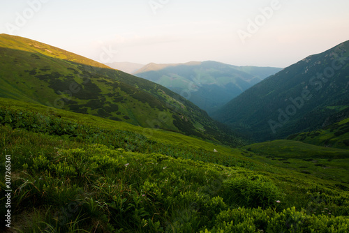 Setting sun shines against hills, beautiful green mountains © Filip