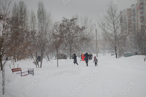 A boy in a ski suit on a snow mountain with a sled. The child is riding a sledge scooter . Active games on the street. Healthy lifestyle