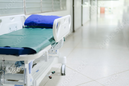 Abstract blurred hospital corridor path way with blank patient bed for background