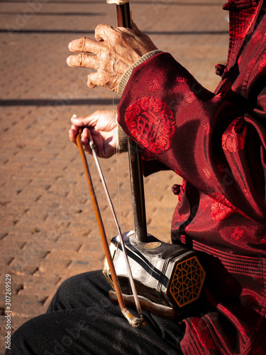 Asian senior man playing an erhu in the street