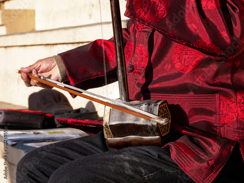Asian senior man playing an erhu in the street photo