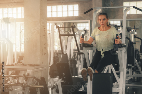 caucasian woman having workout with machine for bodybuilding in fitness club