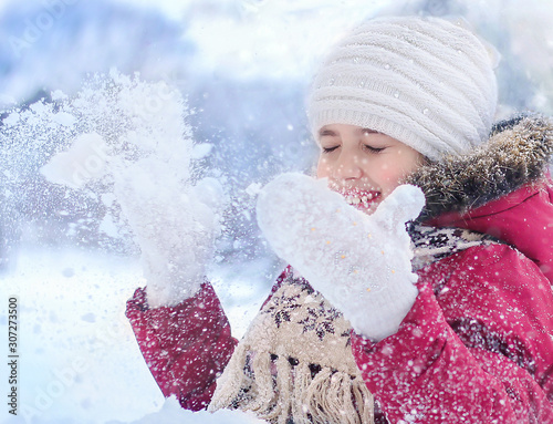 A little girl sits in the snow and plays with the snow.