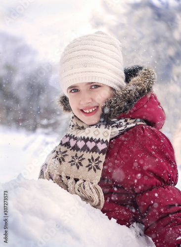 A little girl sits in the snow and plays with the snow.