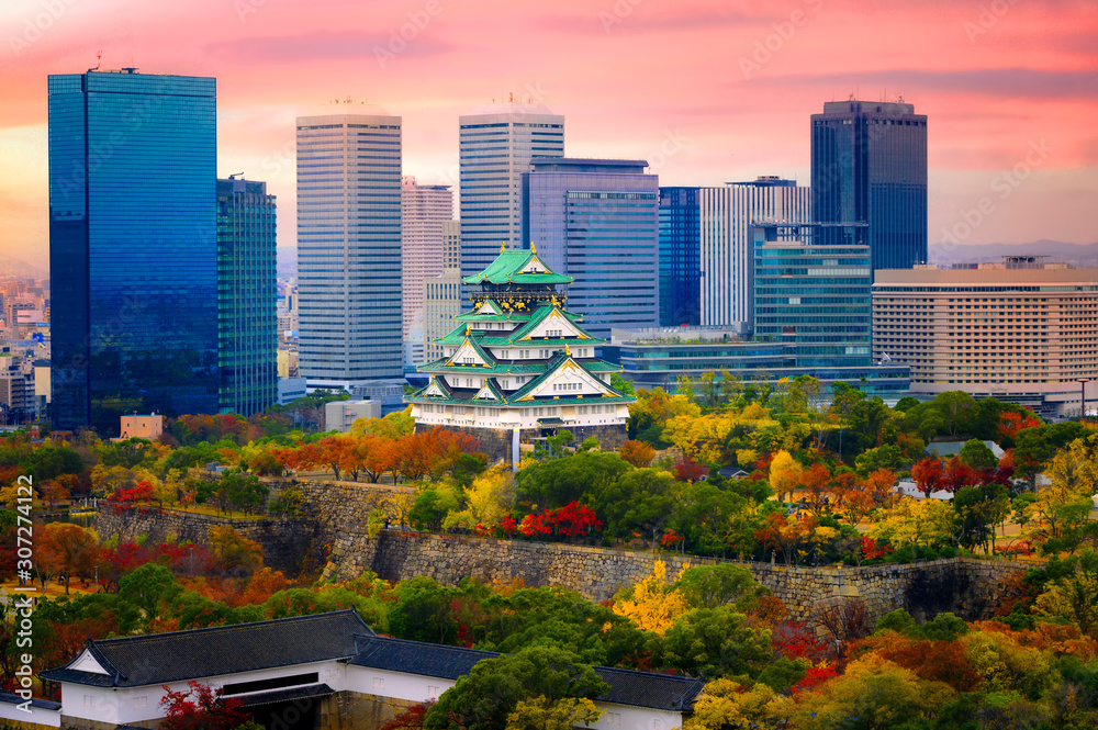 Naklejka premium Zamek w Osace podczas zmiany sezonu jesienią z nowoczesnym budynkiem miejskim obecnym w tle o wschodzie słońca
