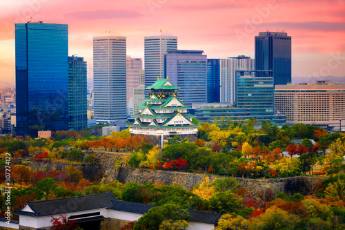 Osaka castle at the season change of autumn with the modern city urban building present in background at sunrise scenery photo