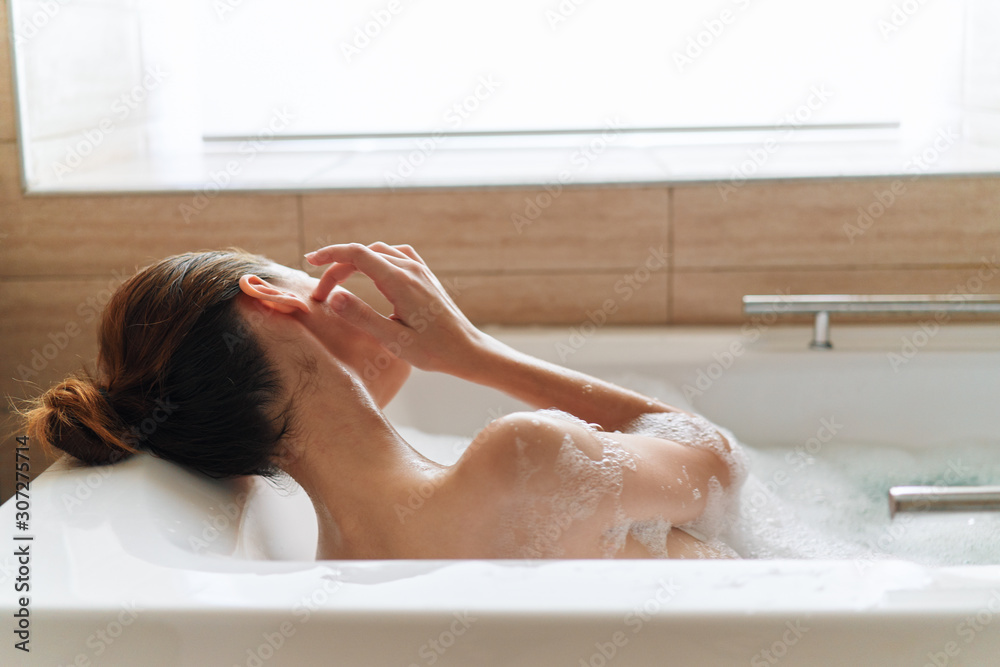 Naklejka premium young woman relaxing in bubble bath