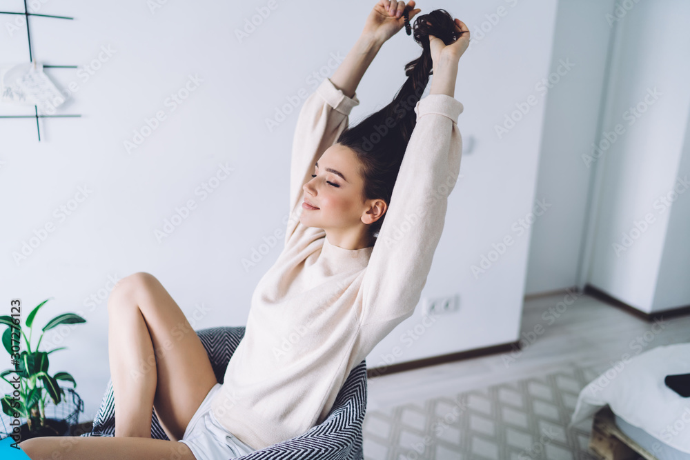 Obraz premium Becalm young woman resting in easy armchair at bedroom