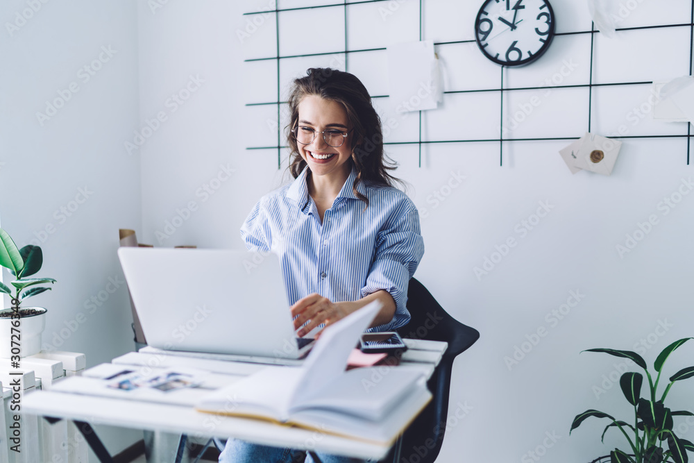 Happy woman working at laptop while sitting at desk Happy woman working at laptop while sitting at desk
