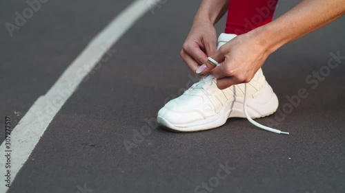Closeup woman lacing up sneakers on track. Fitness girl lacing up shoes