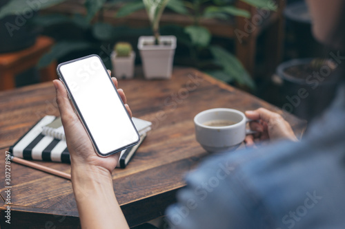 Mockup image blank white screen cell phone.men hand holding texting using mobile on desk at coffee shop.background empty space for advertise text.people contact marketing business and technology 