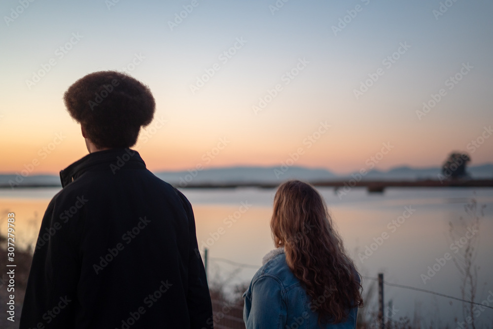 Young Man and Woman Looking to Sunset Young Man and Woman Looking to Sunset